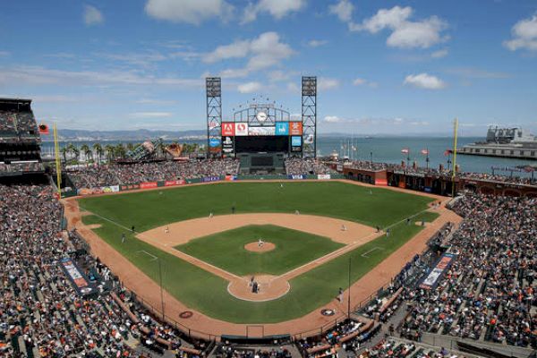 A crowded baseball stadium with a game in progress, showcasing the field, stands filled with spectators, and a scenic water backdrop.