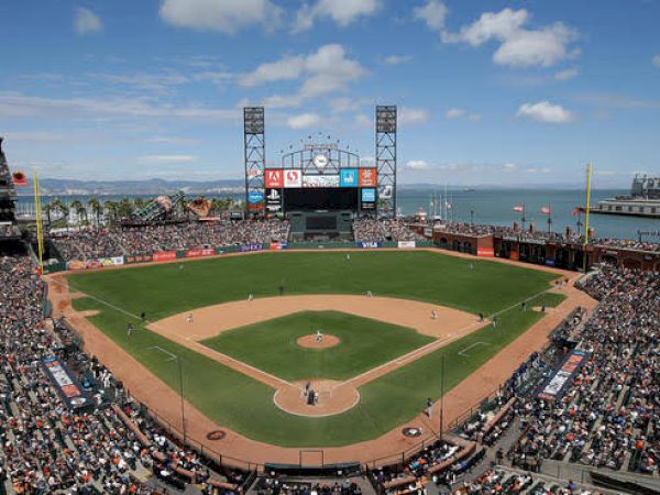 A crowded baseball stadium with a game in progress, showcasing the field, stands filled with spectators, and a scenic water backdrop.